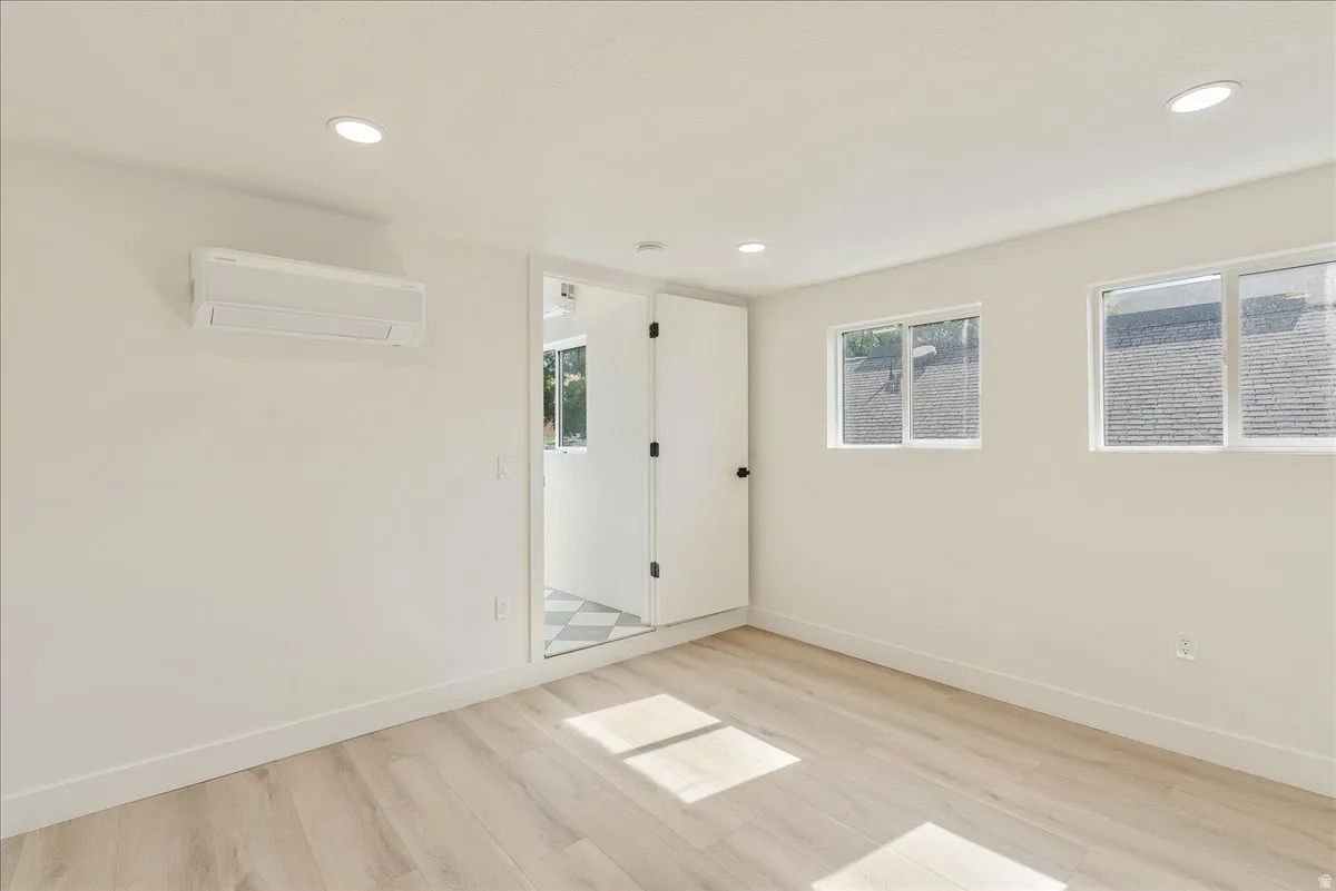 Bright interior space featuring light wood-finish flooring, recessed ceiling lighting, and a white split-system unit