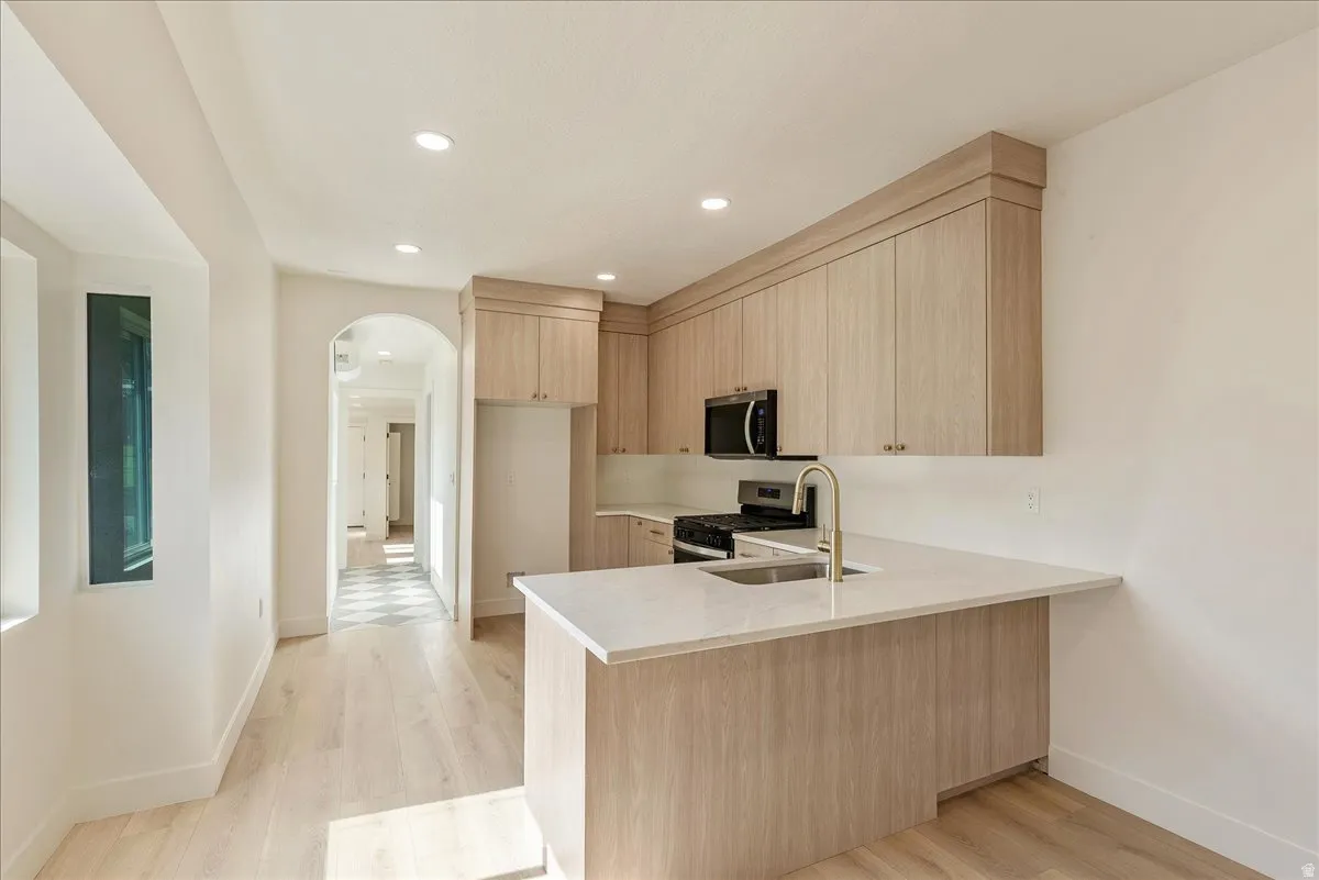 Kitchen featuring light wood-finish cabinetry, a central island with a light-colored countertop, and recessed lighting