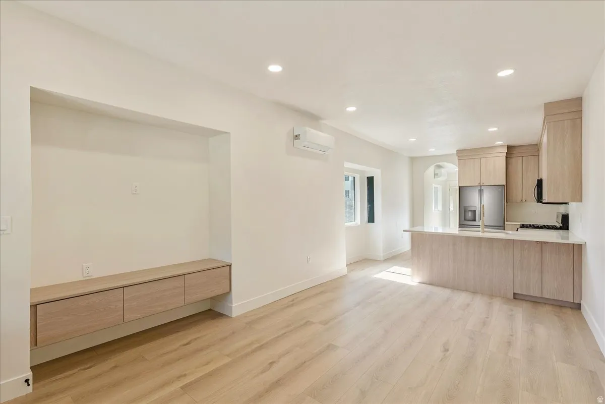 Open-concept living area featuring light wood-finish flooring, recessed lighting, and a built-in media niche with floating cabinetry