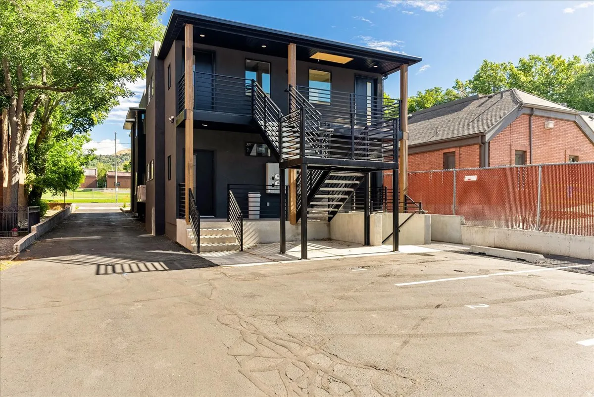 Contemporary multi-story exterior with dark stucco finish, featuring exterior metal staircases and railings