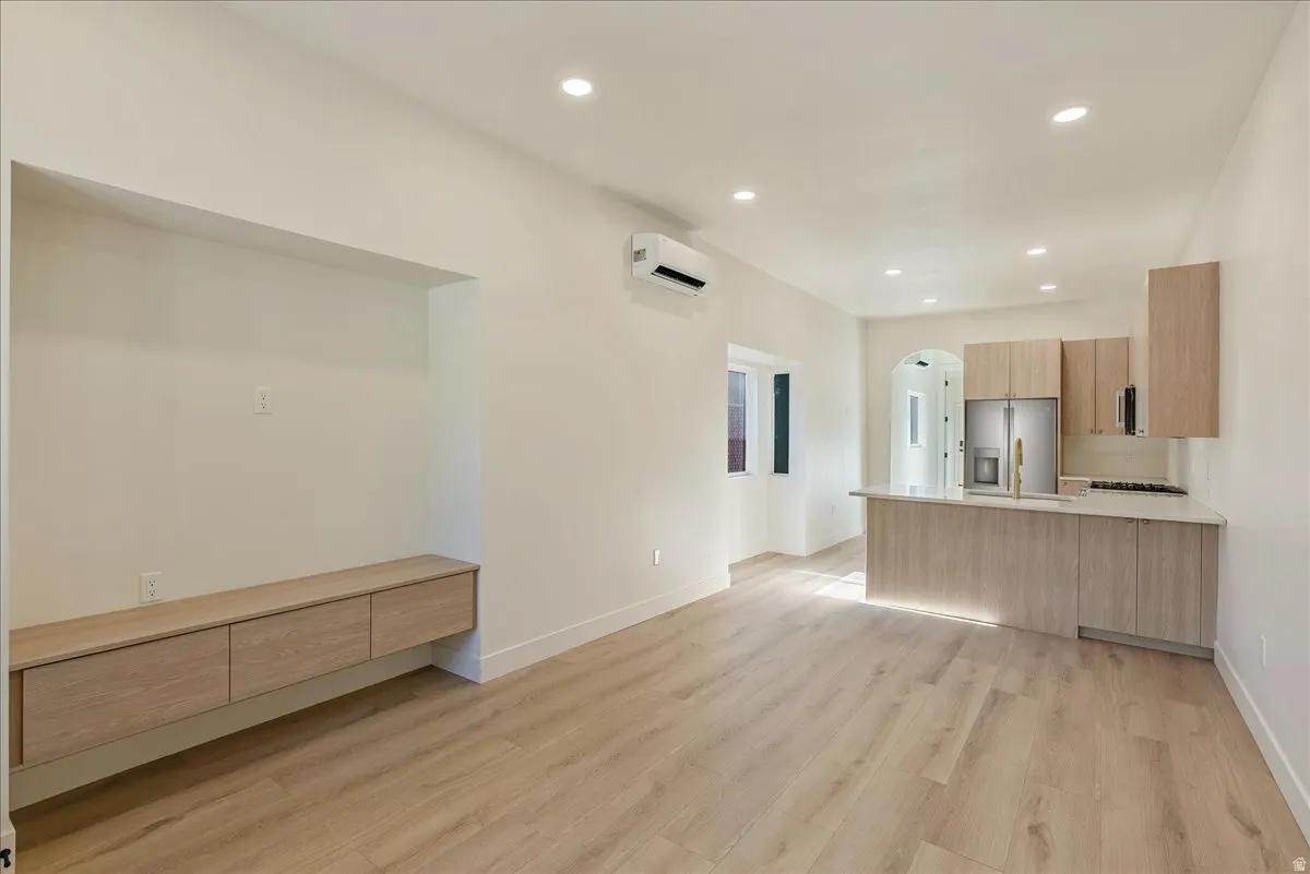 Open-concept living space with light wood-finish flooring, recessed lighting, and a built-in media niche