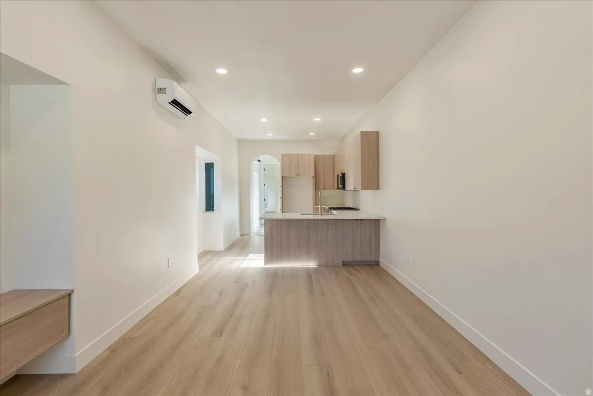 Open-concept living area featuring wood-finish flooring, recessed lighting, and a modern kitchen island with integrated sink