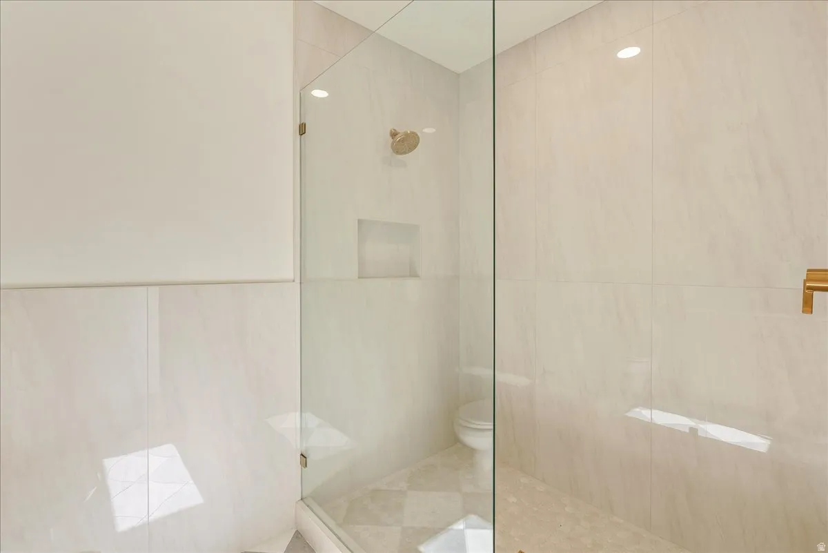 Glass-enclosed shower featuring a built-in bench, recessed shower niche, and a gold-finish shower head