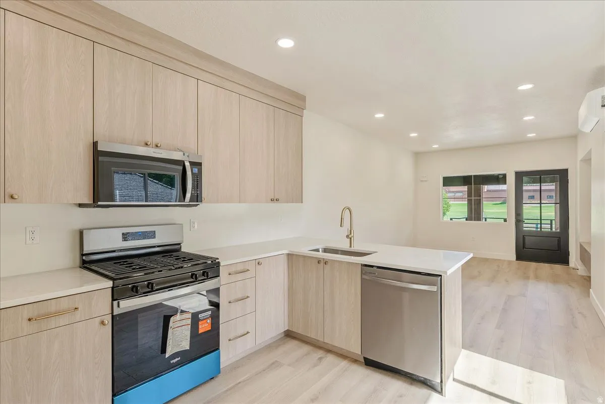Modern kitchen featuring light wood-finish cabinetry, stainless steel appliances, a gas range, and recessed lighting