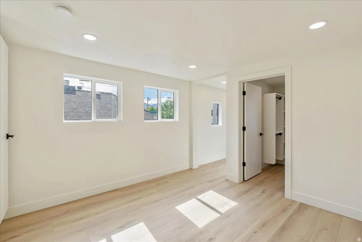 Bright room featuring light wood-finish flooring, white walls, and recessed ceiling lighting
