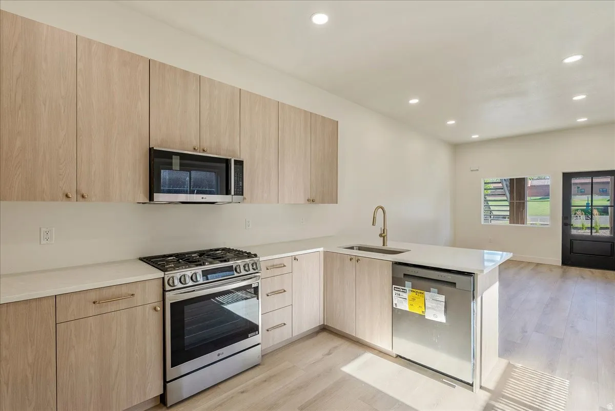 Modern kitchen featuring wood-finish cabinetry, stainless steel appliances, a gas range, a built-in microwave, and recessed lighting