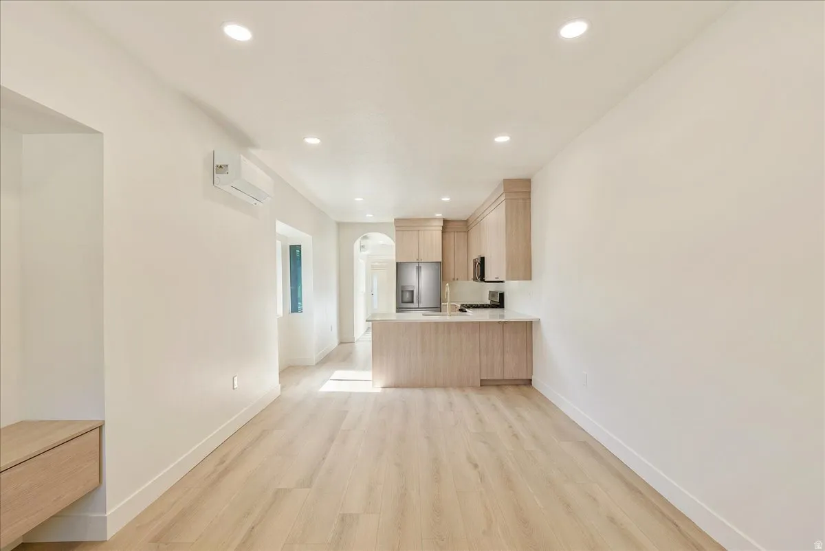 Open-concept living space featuring wood-finish flooring, recessed lighting, and a modern kitchen