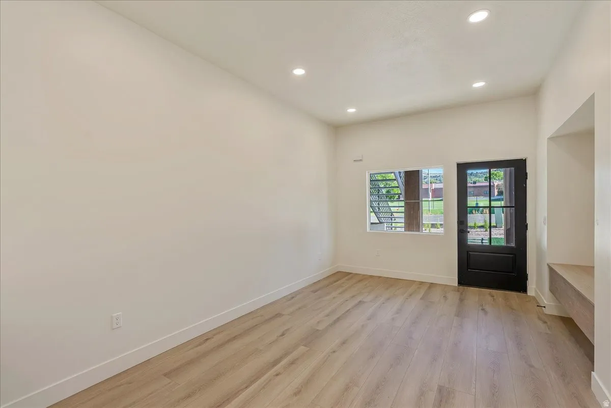 Spacious room featuring wood-finish flooring, recessed lighting, and white baseboards