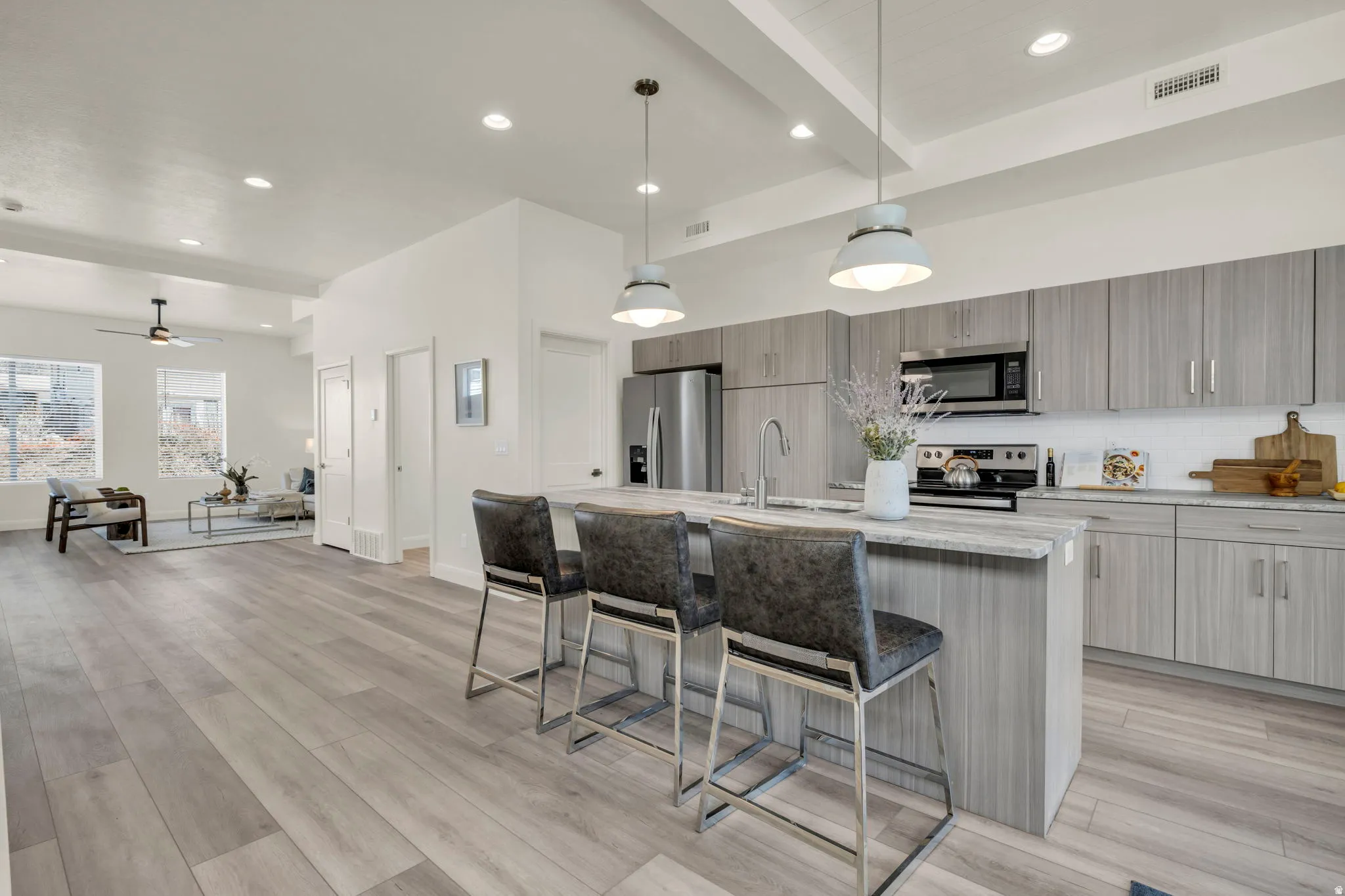 Open-concept kitchen featuring an island with seating, stainless steel appliances, wood-finish cabinetry, and recessed lighting