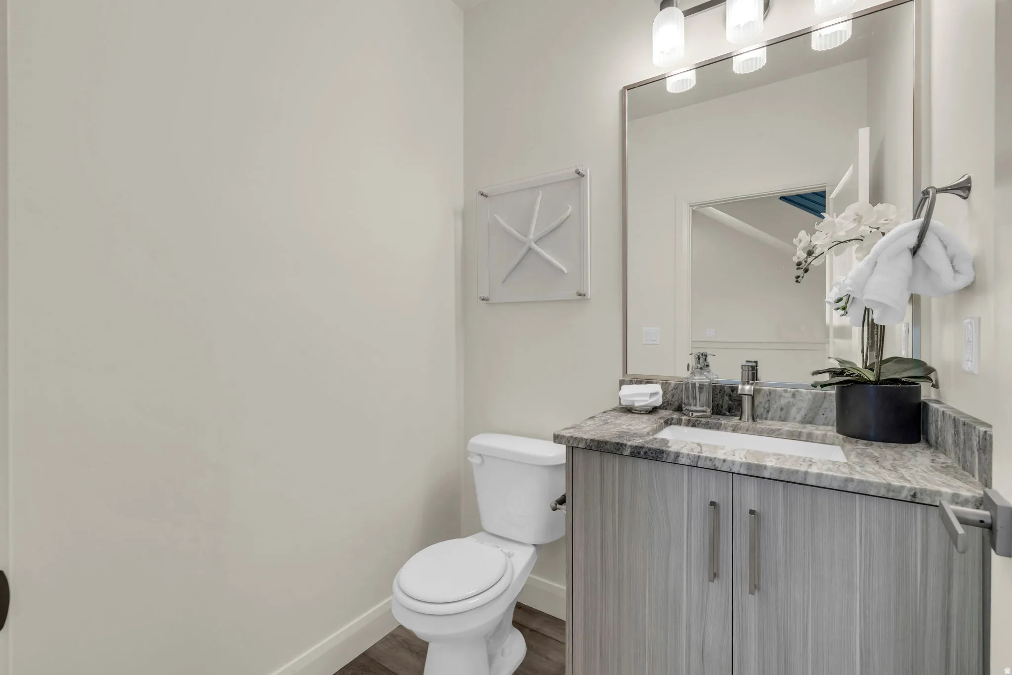 Bathroom featuring a wood-finish vanity with a stone countertop, an undermount sink, and a framed mirror
