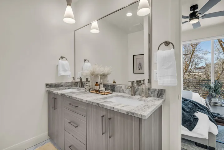 Double vanity with gray wood-finish cabinetry, integrated sinks, and polished chrome faucets