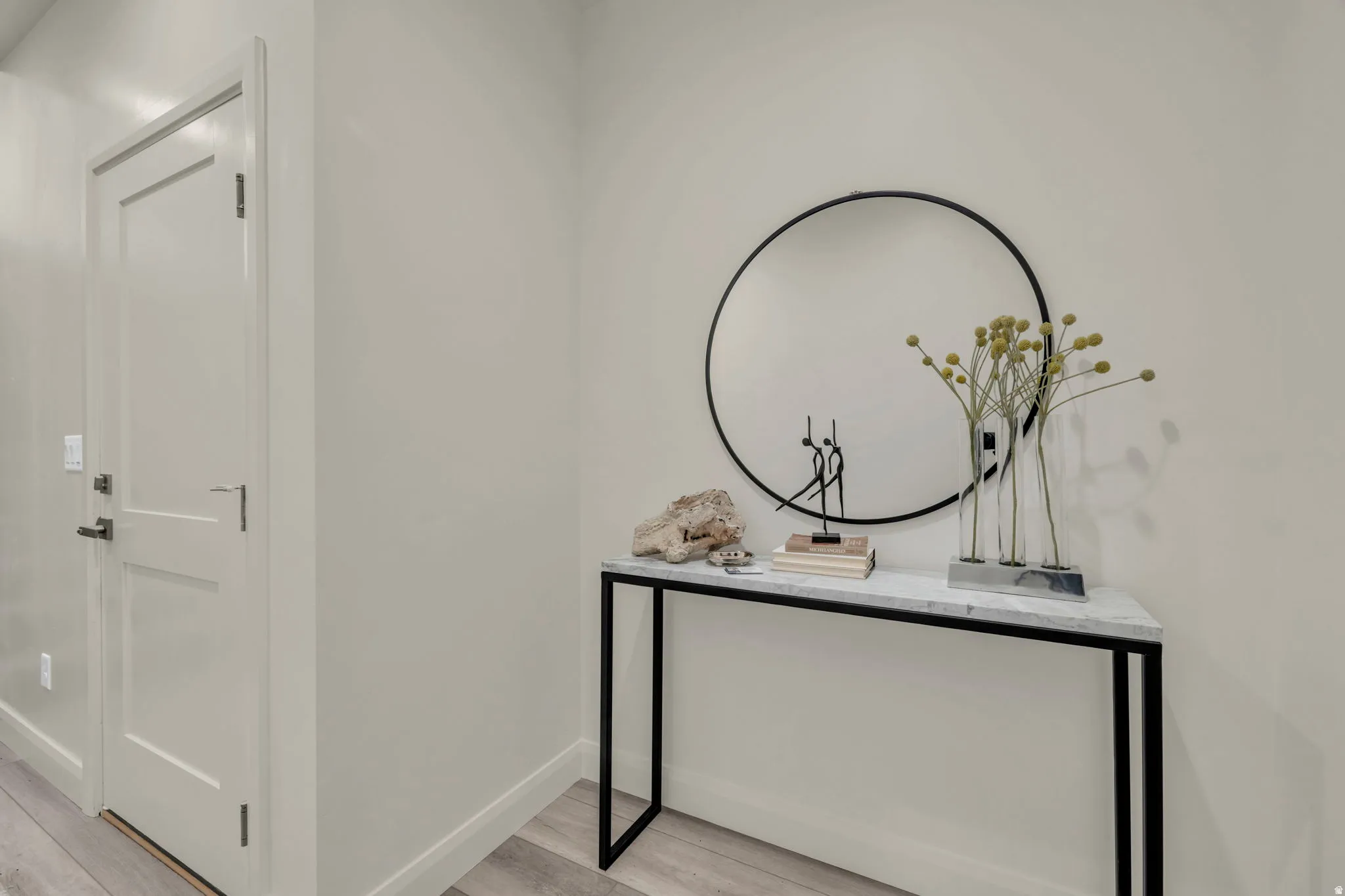 Crisp white walls with streamlined baseboards, wood-finish flooring, and a modern two-panel interior door with matte black hardware