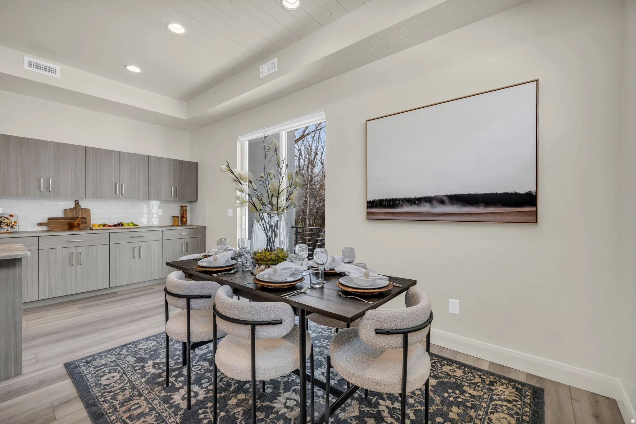 Dining area featuring wood-finish flooring, a tray ceiling with recessed lighting, and a sliding glass door