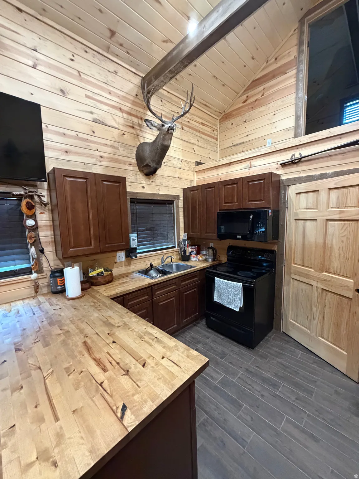 Vaulted planked wood ceiling with exposed beam, wood-finish wall paneling, and wood-finish flooring