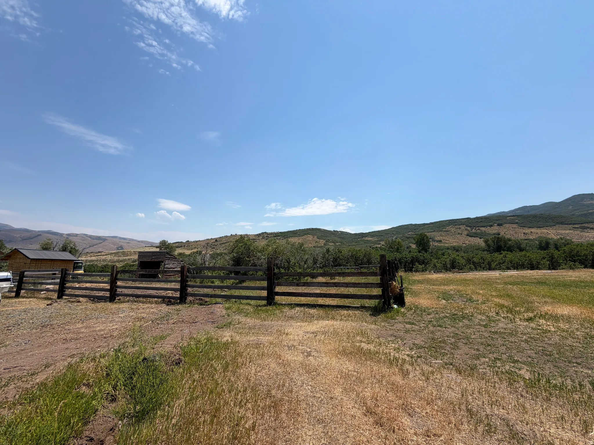 Expansive fenced area with a single-story structure and distant mountain scenery