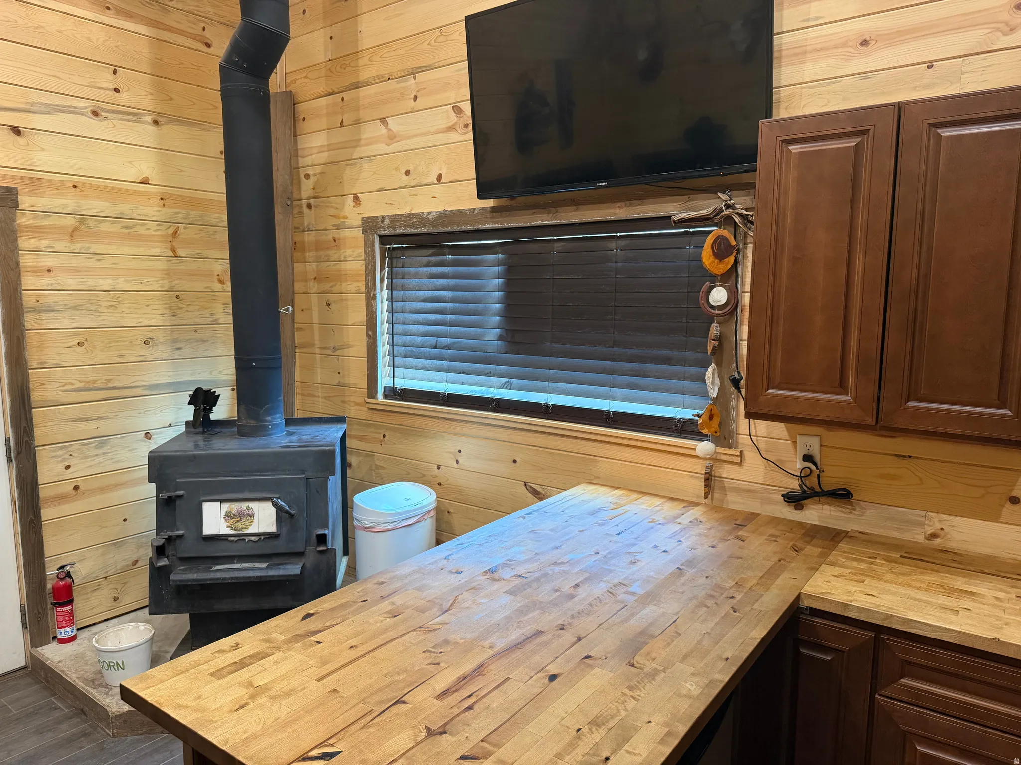 Wood-paneled interior featuring a black wood-burning stove with metal flue and a built-in window with dark blinds