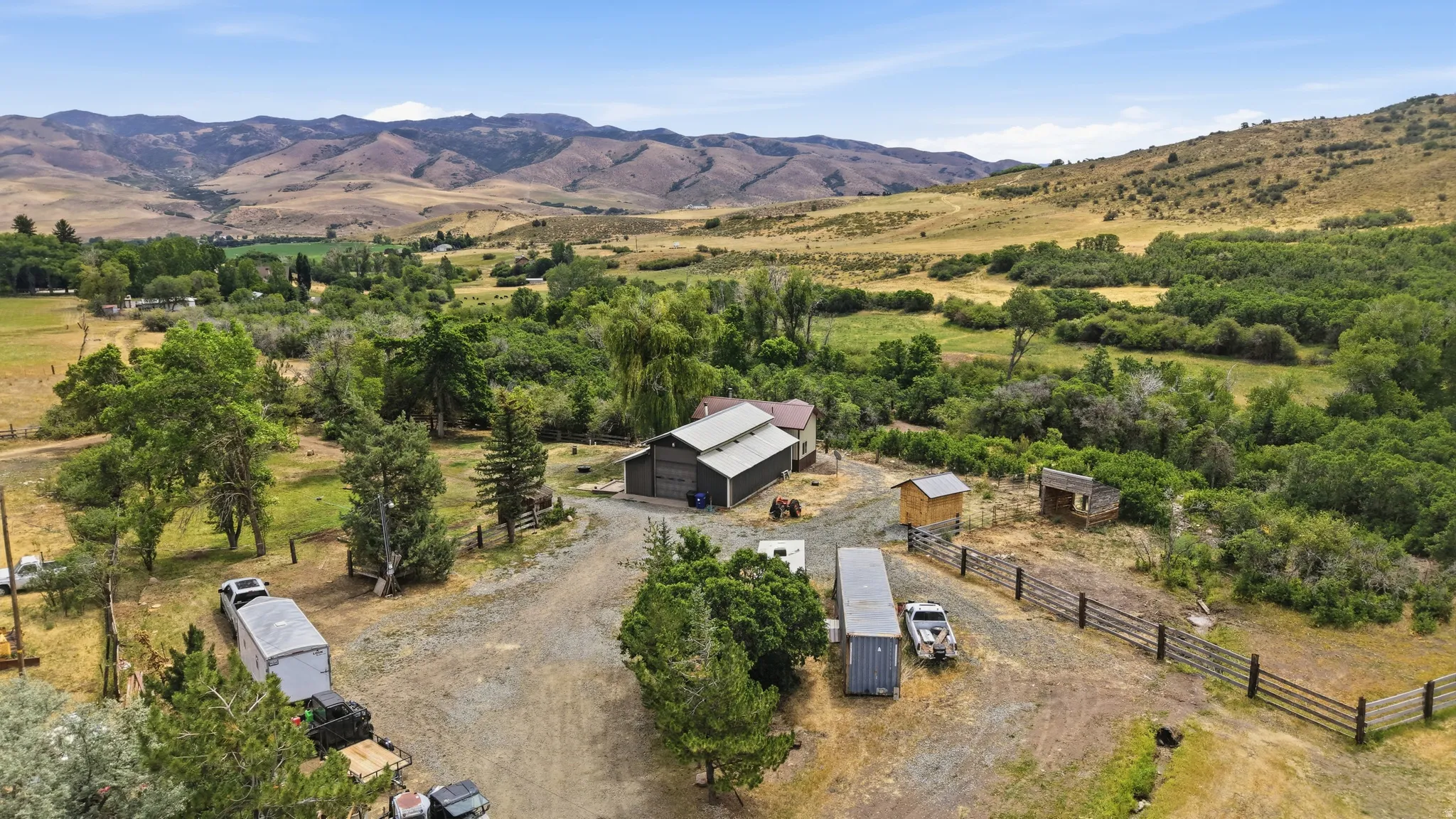 Expansive property featuring a central barn structure, multiple outbuildings, and natural landscaping