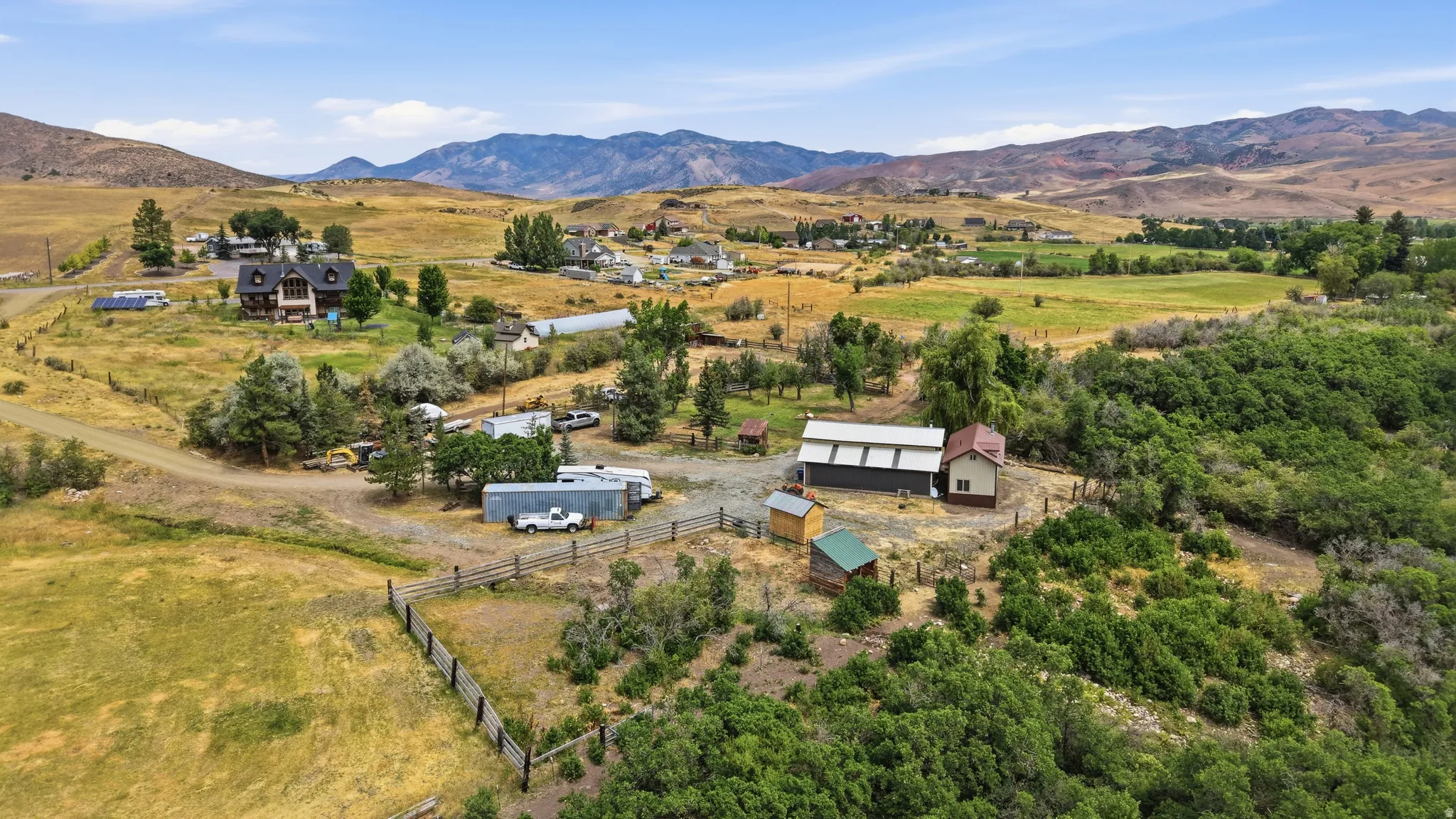 Expansive property with multiple structures, including a two-story residence, a large outbuilding with a metal roof, and several smaller ancillary structures