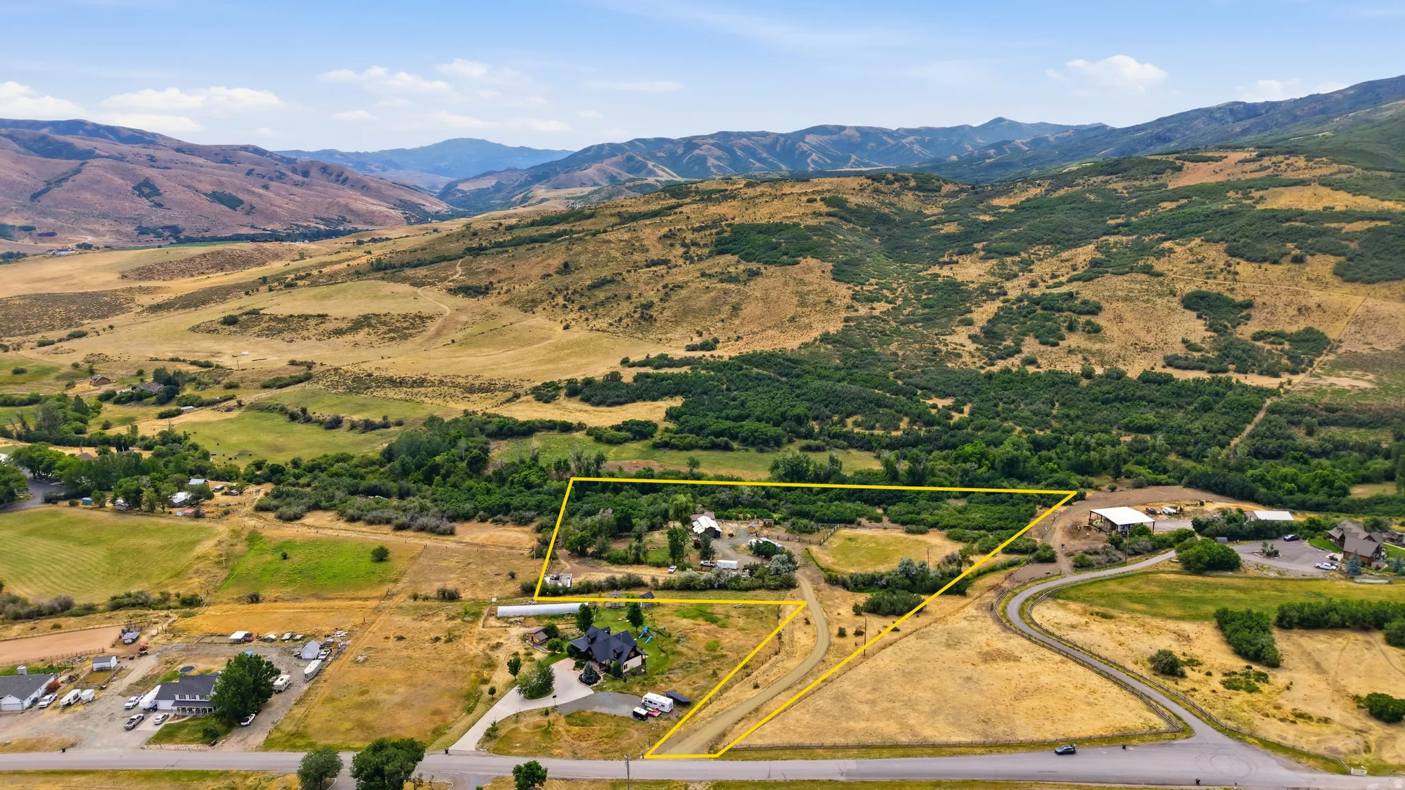 Expansive rural property featuring multiple structures, open land, and mountain backdrops