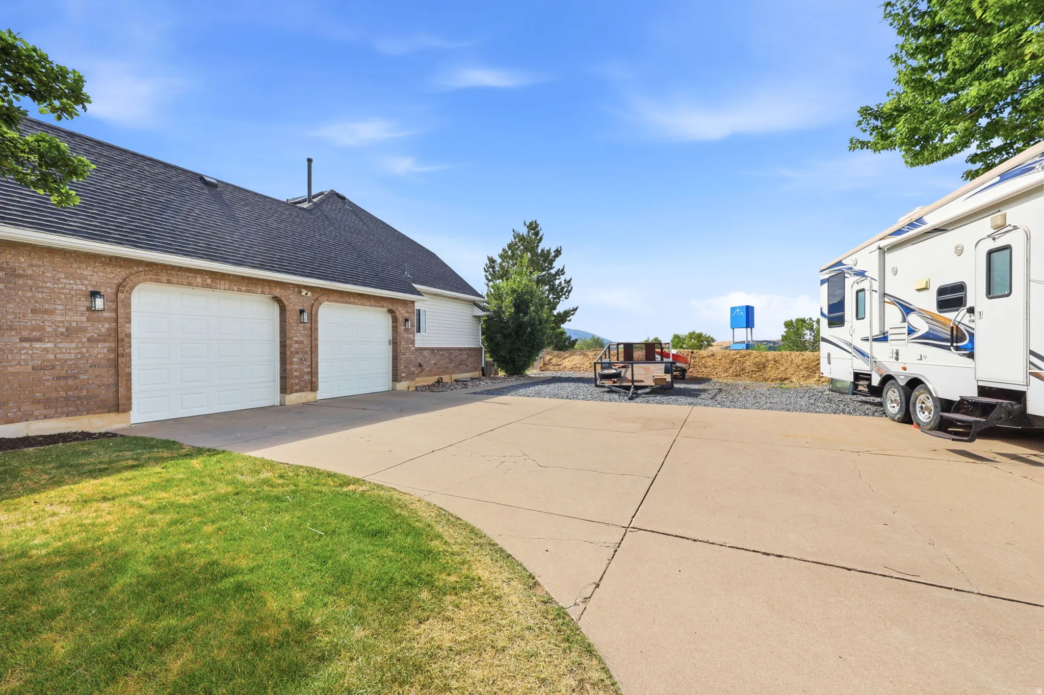 Brick exterior featuring two arched garage door openings with white panel doors and black wall-mounted light fixtures