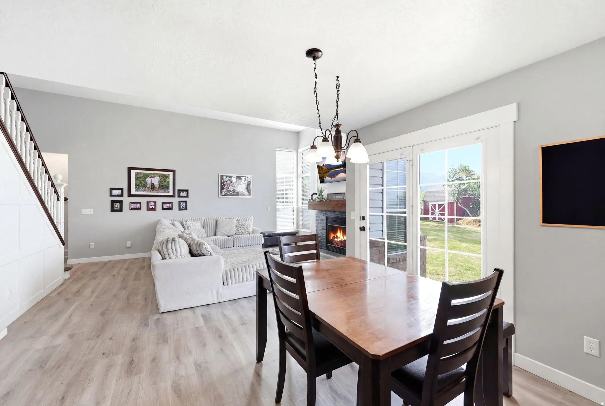 Open concept living area featuring wood-finish flooring, a modern fireplace, white trim details, and sliding glass doors
