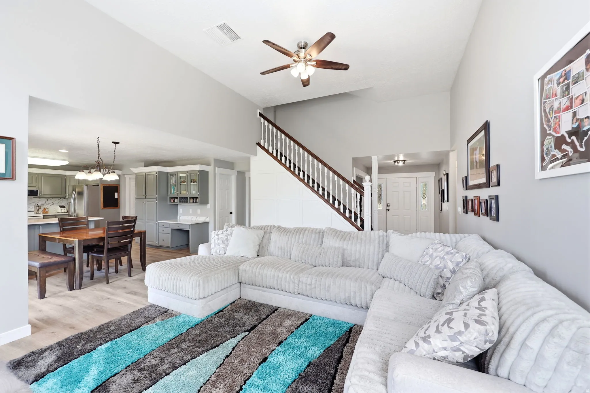 Open-concept living area with wood-finish flooring, vaulted ceilings, and a ceiling fan
