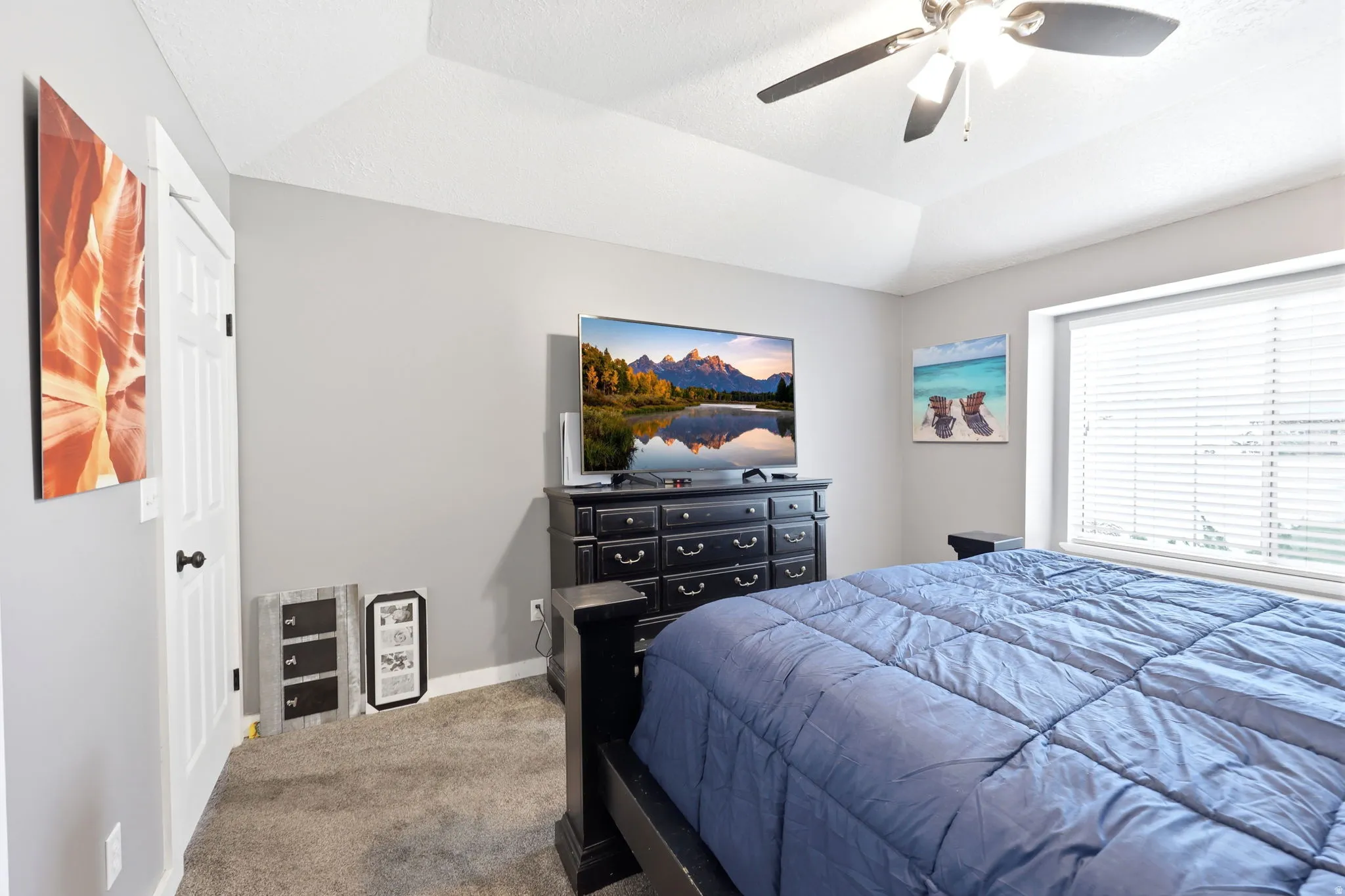 Tray ceiling with a ceiling fan, light gray wall paint, and carpet flooring