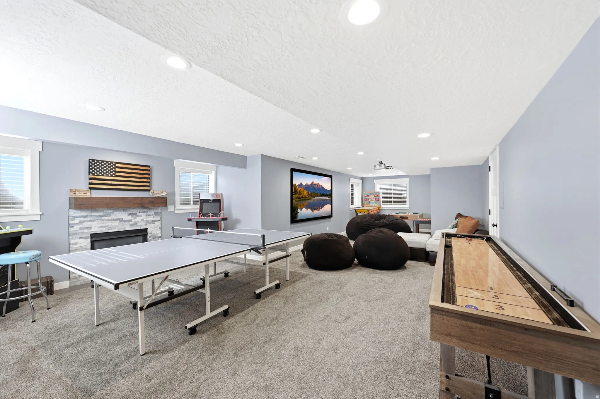 Carpeted entertainment area featuring a fireplace with stone surround, a wood mantel, and recessed lighting