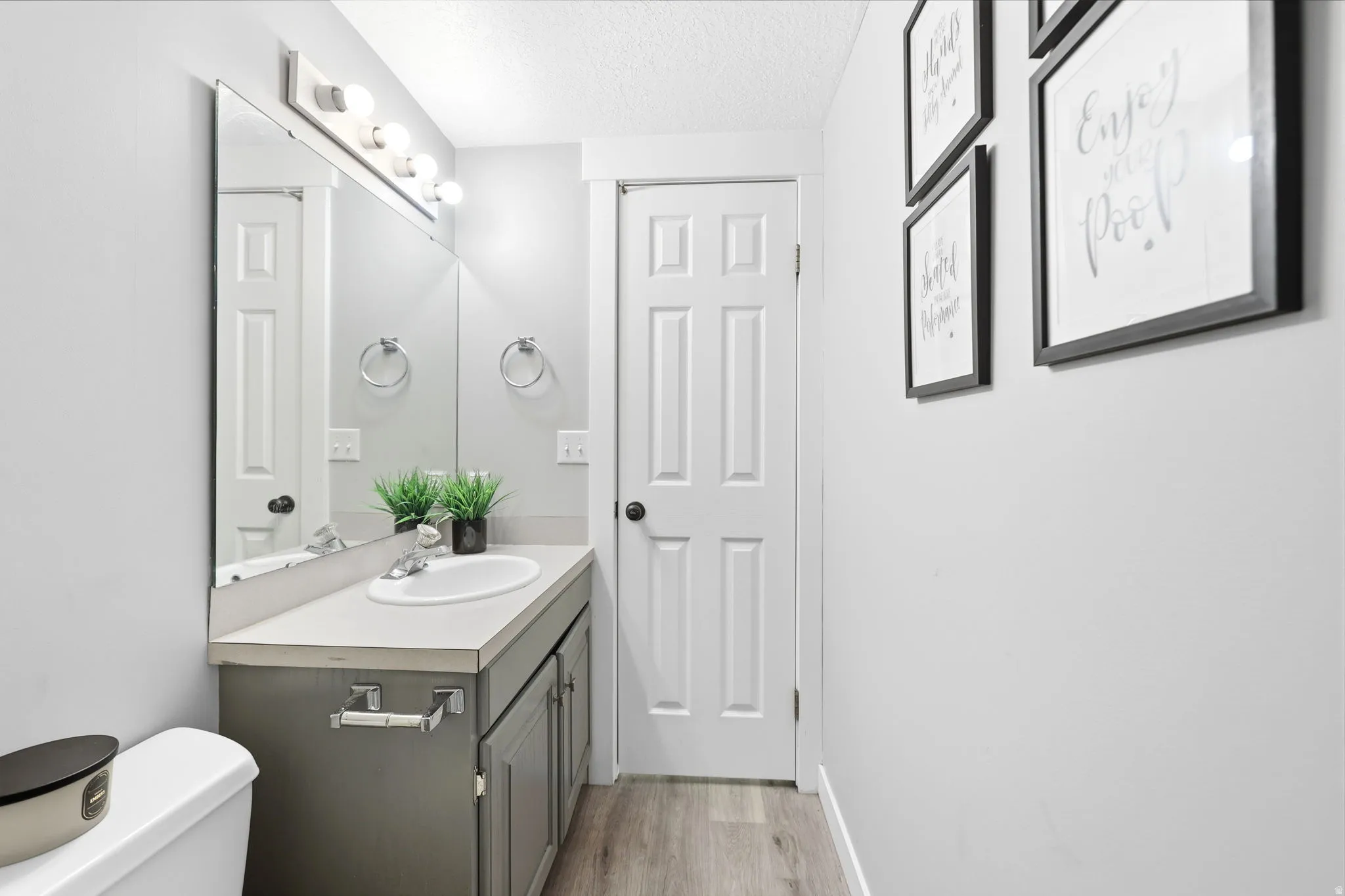Bathroom featuring a built-in vanity with a single basin sink and gray cabinetry, a wide mirror, and an overhead light fixture