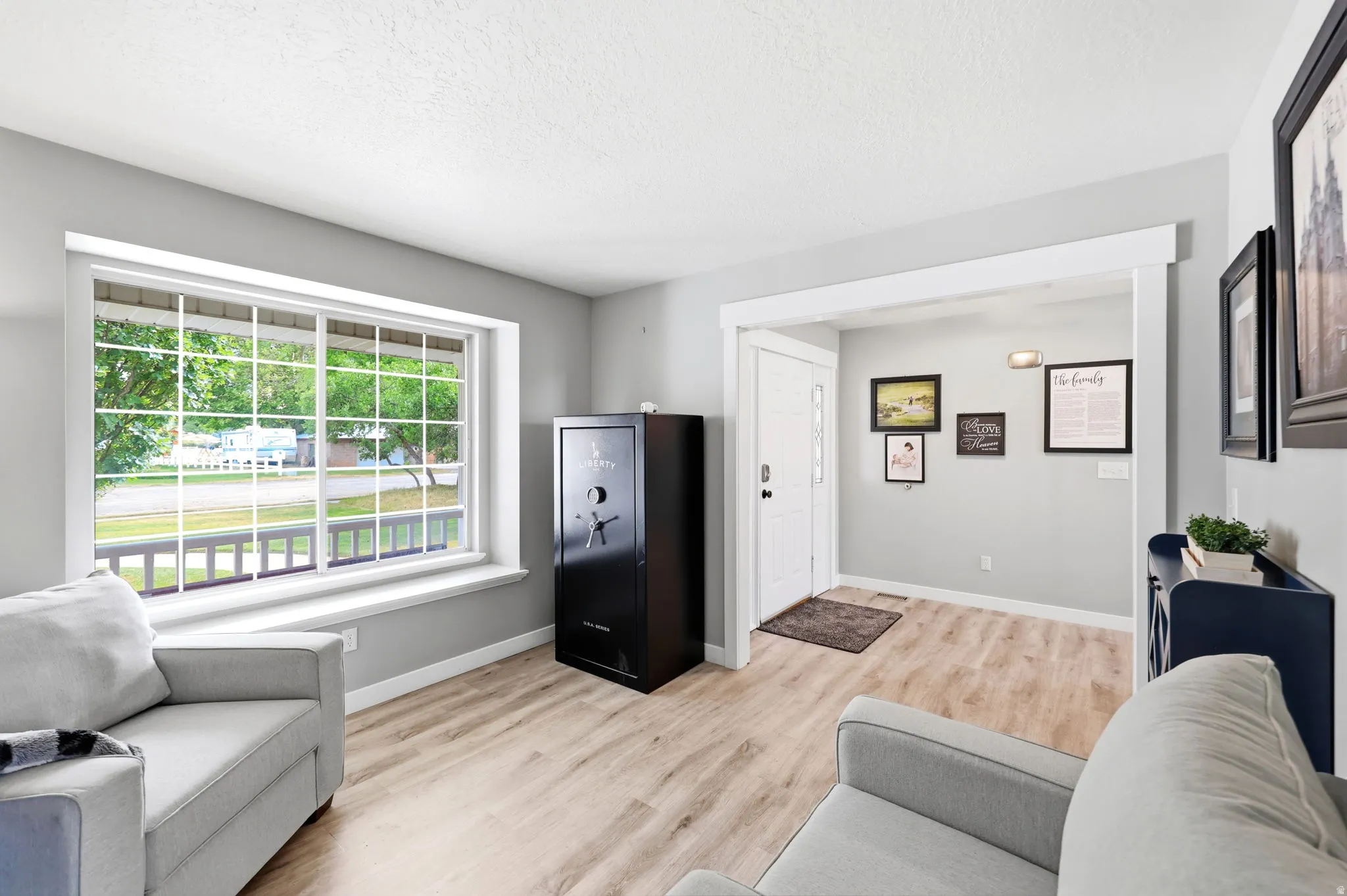 Spacious room with light wood-finish flooring, a large window featuring white grid panes, and a crisp white trim package