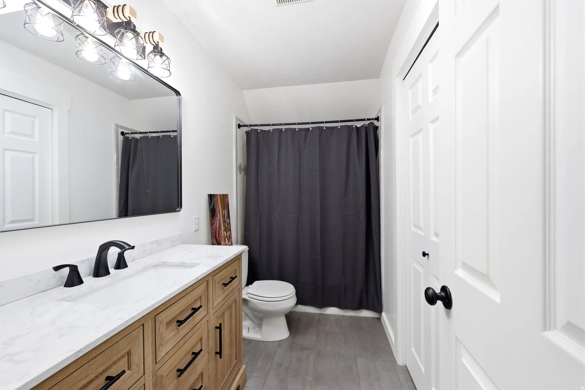 Bathroom featuring a light wood-finish vanity with a white countertop and matte black fixtures