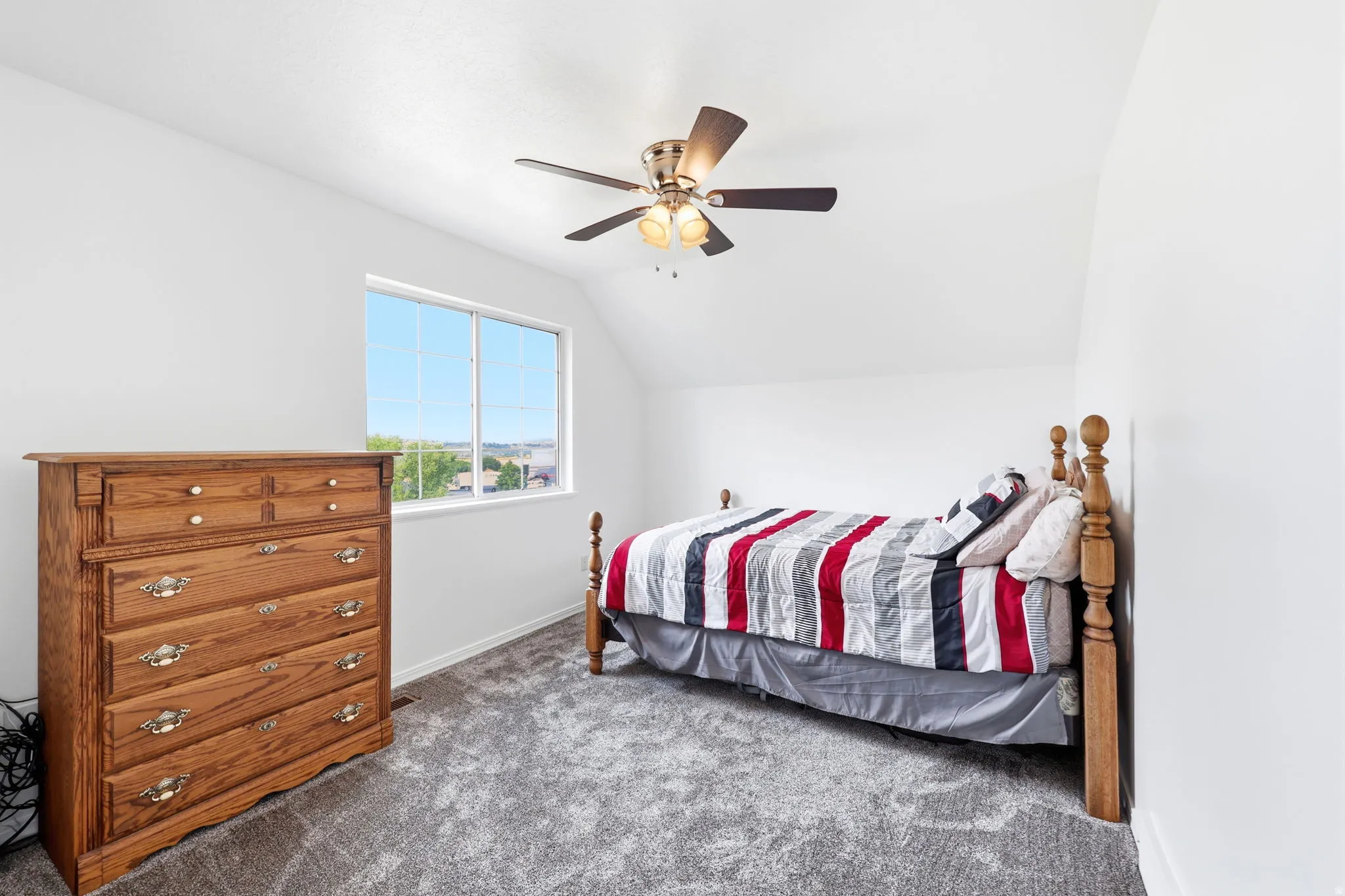 Light-filled room featuring a rectangular window, a ceiling fan with light fixture, and grey carpet flooring
