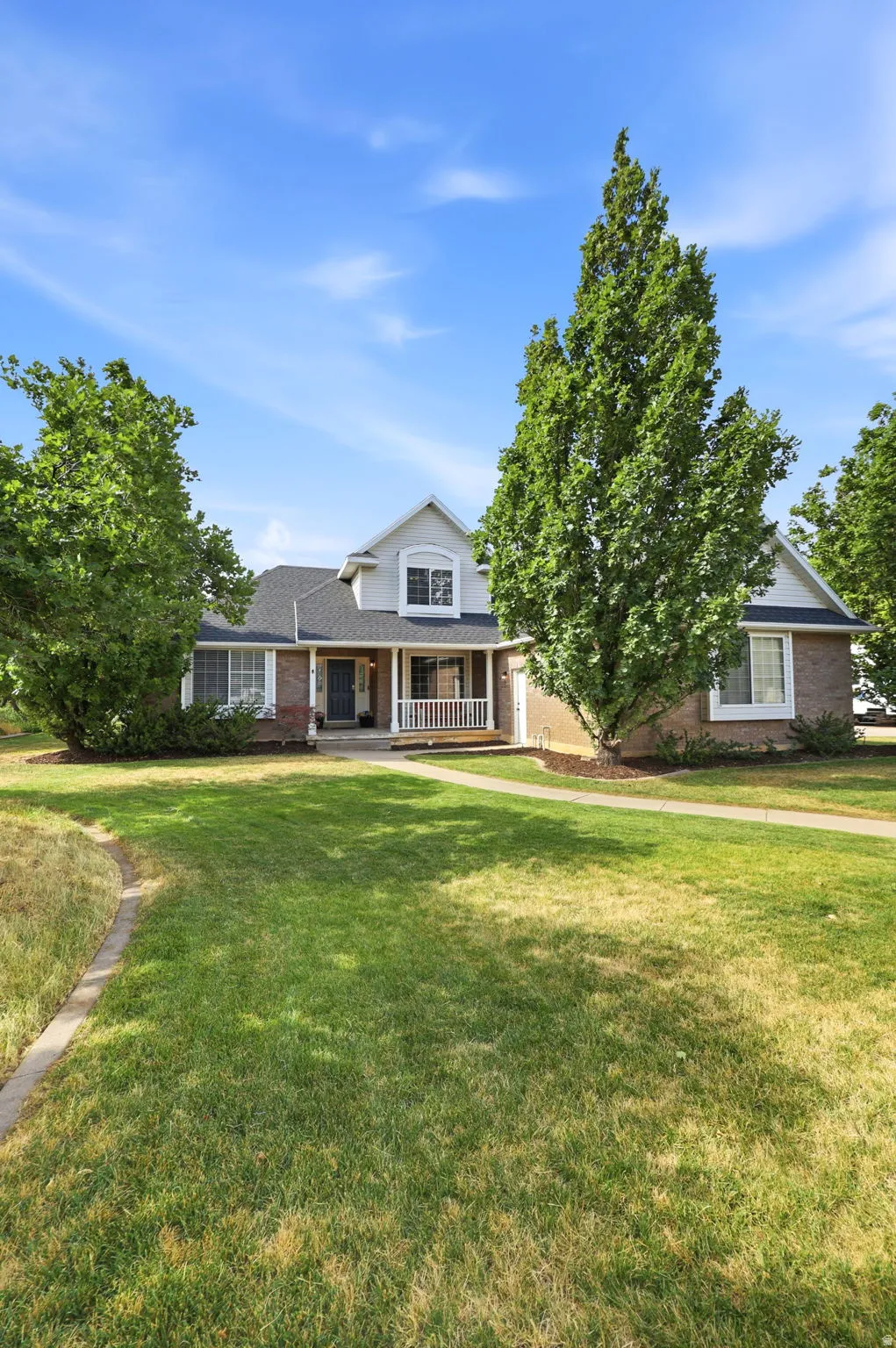 Expansive front lawn with mature trees framing a traditional two-story residence