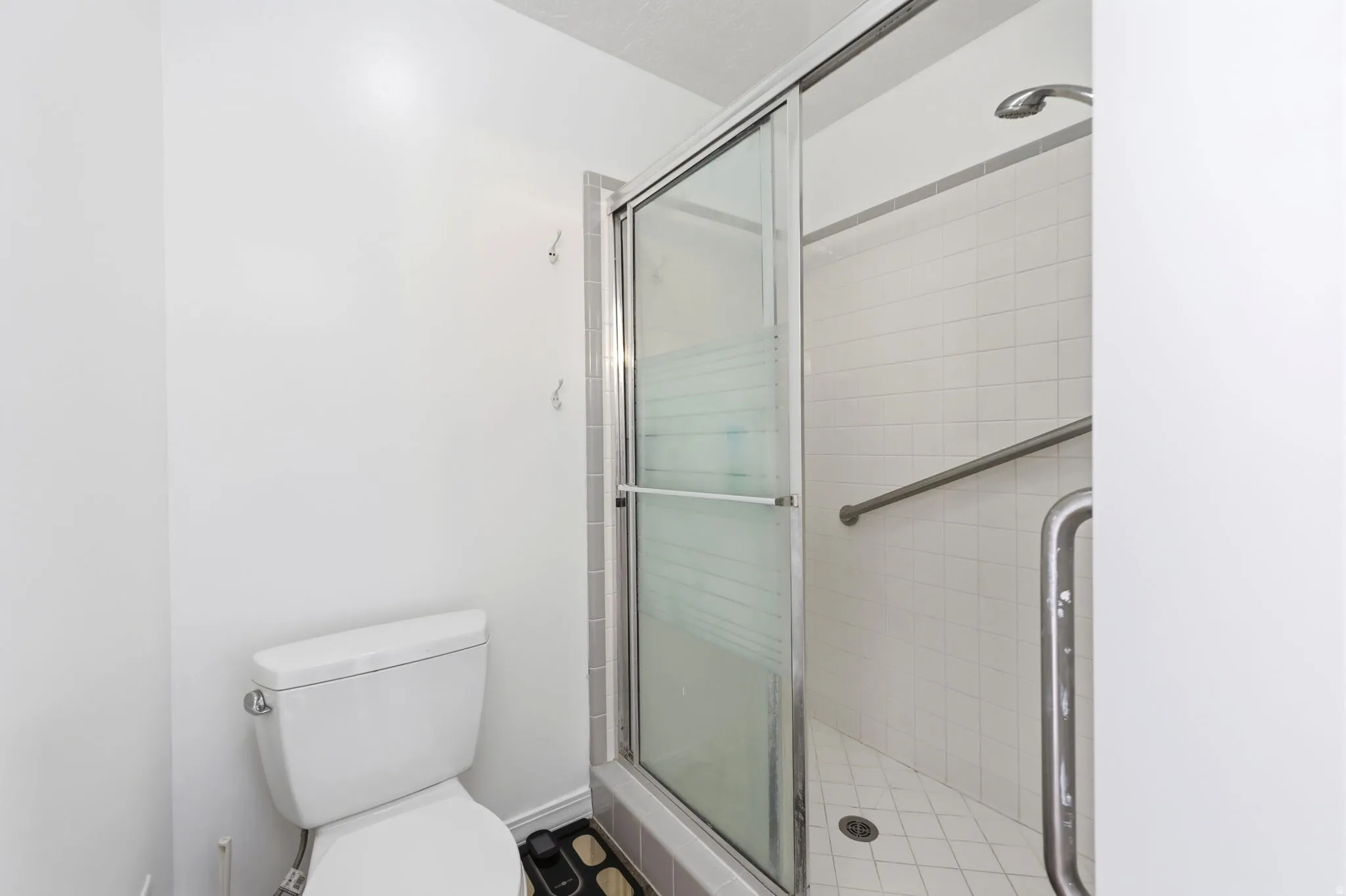 Shower with a sliding glass door, white subway tile surround, and a metal grab bar