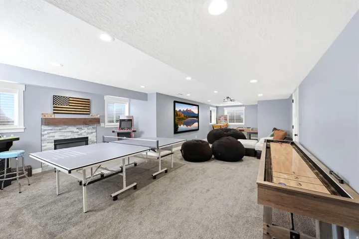 Carpeted entertainment area featuring a fireplace with stone surround, a wood mantel, and recessed lighting