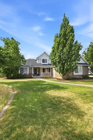 Expansive front lawn with mature trees framing a traditional two-story residence