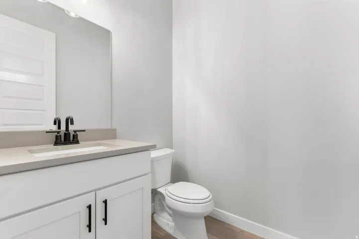 White vanity featuring a light-toned countertop, integrated sink, and matte black faucet