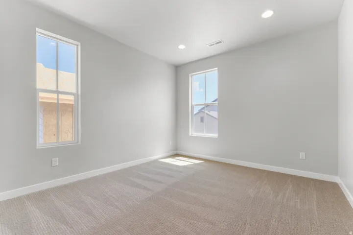 Spacious room featuring neutral carpeting, light gray wall paint, and white trim