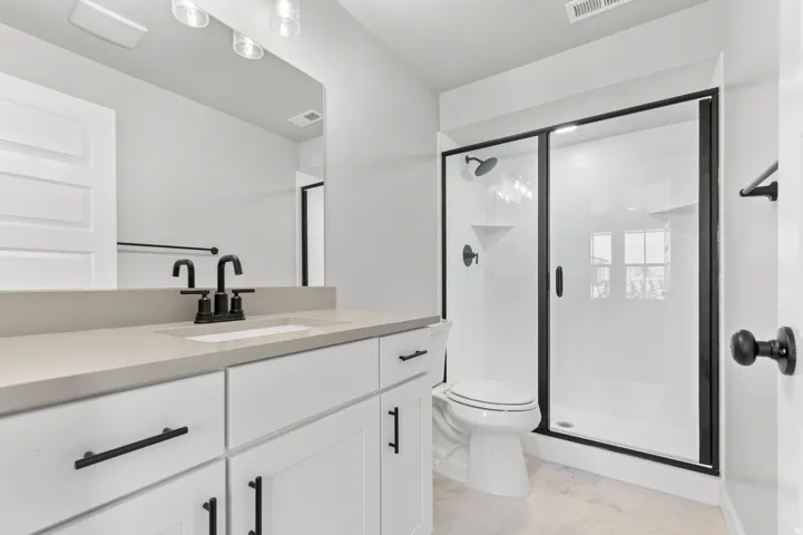 White cabinetry vanity with a light-toned countertop, matte black fixtures, and a framed mirror