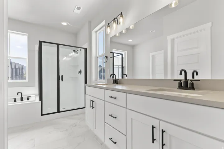 Spacious bathroom featuring a dual vanity with undermount sinks, stone countertops, and matte black hardware