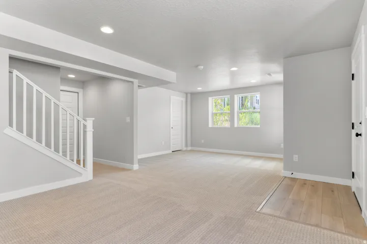 Spacious interior room featuring light-toned carpeting and wood-finish flooring