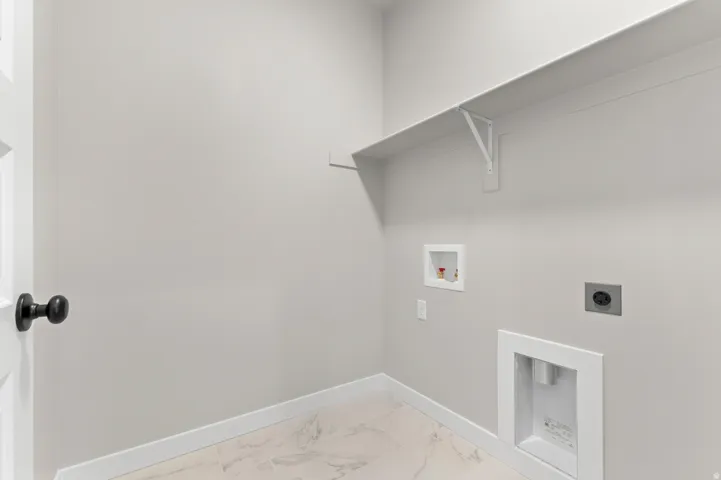 Dedicated utility space featuring white marble-look tile flooring, light gray wall paint, and crisp white baseboards