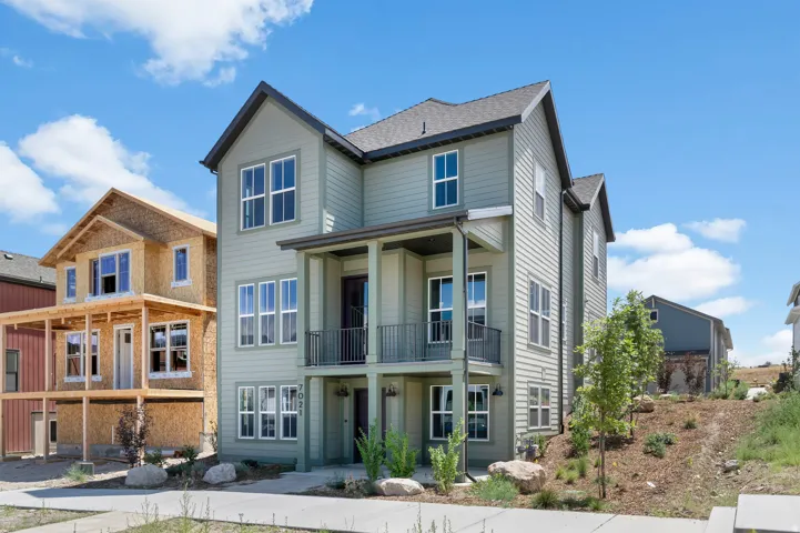 Three-story residence featuring light green horizontal siding and a dark gray shingled roof