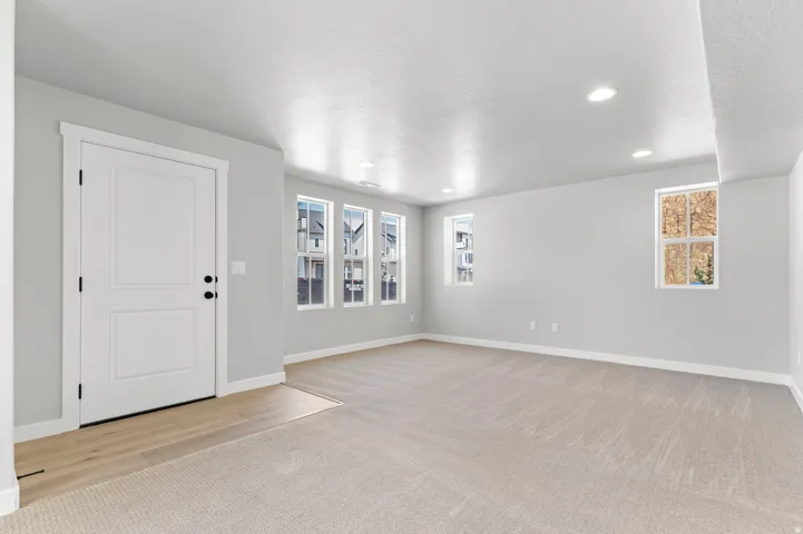 Spacious room featuring light gray walls, recessed lighting, and soft neutral carpeting