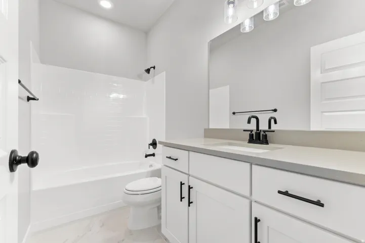 Bathroom featuring a white subway tile shower surround, a white bathtub, and a vanity with a light-toned countertop