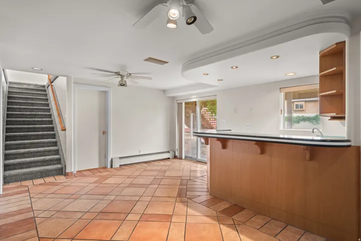 Interior space featuring terracotta tile flooring with a geometric pattern, a built-in wet bar with wood-finish cabinetry, integrated shelving, and recessed lighting