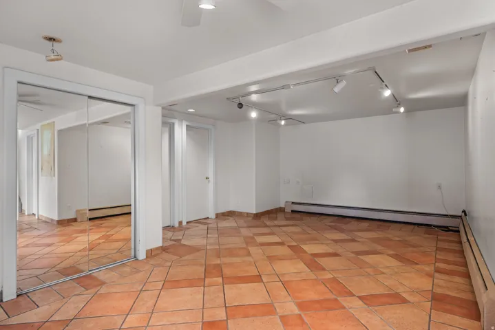 Spacious room with patterned terra cotta tile flooring, white walls, and built-in track lighting