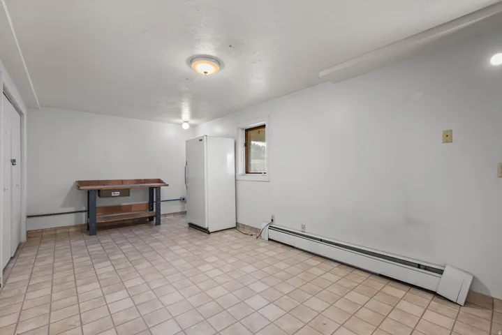 Spacious room featuring tile flooring, white painted walls, and a window with exterior visibility