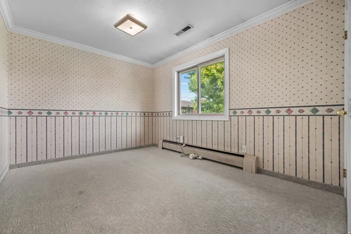 Room featuring a window, textured wallpaper, carpet flooring, baseboard heating, and a ceiling light fixture