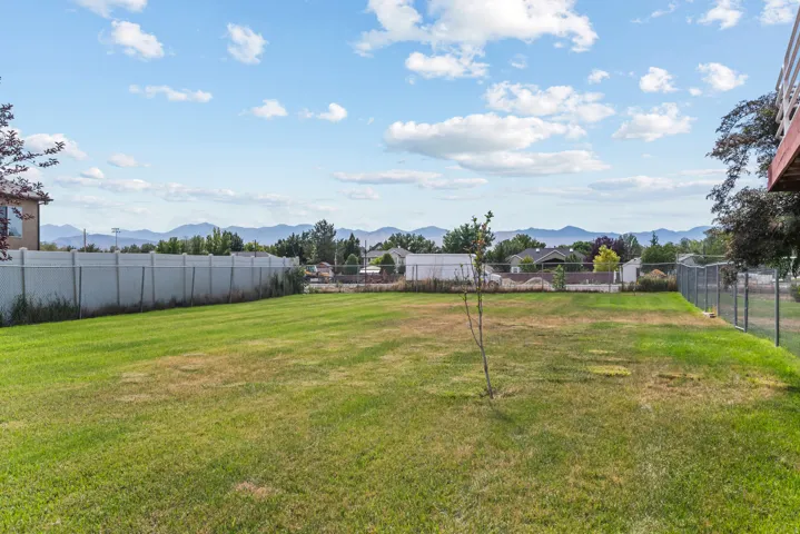 Expansive green lawn with mountain scenery and partial fencing